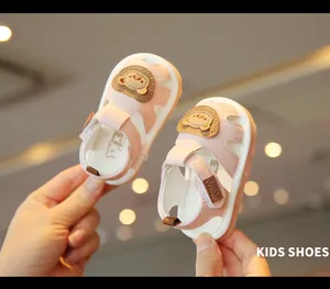 Macro view of cute pink baby walking sandals with cartoon bear design and velcro straps.