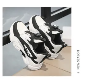 Detail view of children's white and black sports sneakers with rotary knob lacing