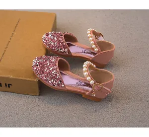Close-up of pink sequined girls' princess shoes with pearl straps and metal charms