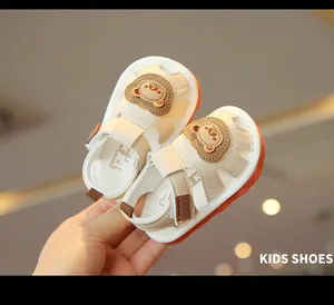 Detail view of cream baby sandals with cute cartoon bear design and soft non-slip soles.