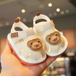 Cute white baby toddler sandals with cartoon bear patch and soft orange non-slip soles.