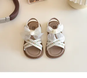 Detalle de sandalias blancas para niñas con lazos de organza y bordado floral