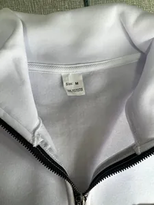 Macro view of white fleece sweatshirt neck label showing Size M and 100% polyester