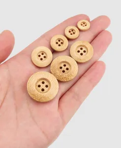 Gros plan de boutons ronds en bambou naturel à quatre trous de tailles variées pour habits
