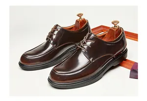 Vista detallada de elegantes zapatos Derby de cuero brillante marrón para hombre.
