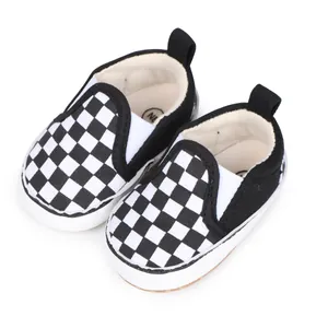 Detalle de los zapatos de lona para bebés con cuadros blancos y negros y una suela blanca blanda