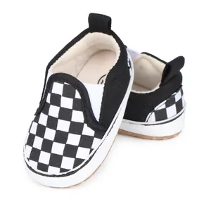 Primer plano de zapatos de lona para bebé con patrón de cuadros blancos y negros y suela blanda