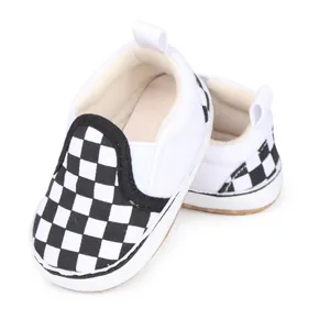 Primer plano de zapatos de lona para bebé con patrón de cuadros blancos y negros y suela blanda
