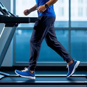 Detailed side view of men's navy blue joggers being worn while running on a treadmill
