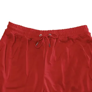 Detail view of red men's sweatpants featuring elastic drawstring waistband with metal tips