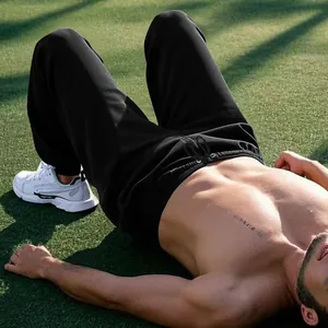Macro view of black men's training joggers worn by a model in an outdoor fitness setting
