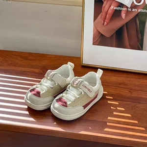 Zapatillas de malla transpirable para niños en beige y burdeos sobre mesa madera