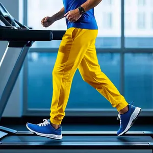 Professional side view of men's bright yellow joggers running on a gym treadmill