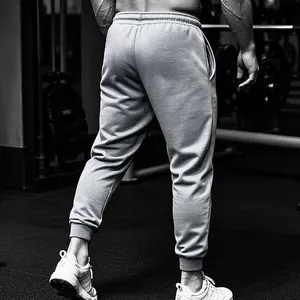 Achteraanzicht van een comfortabele grijze joggingbroek voor heren in een fitnessomgeving.