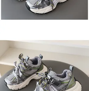 Detail of children's grey mesh breathable sneakers with stylish green accents and chunky soles.