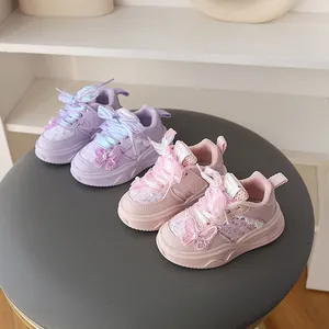 Primer plano de zapatillas con purpurina rosa y morada para niña con lazo de mariposa