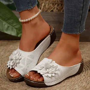 Vue détaillée des mules à talons compensés blancs avec fleurs 3D et perforations