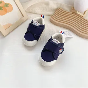 Vista detallada de zapatos de bebé azul marino y blanco con suelas blandas y velcro