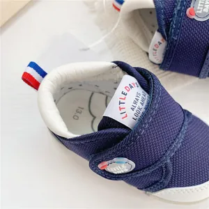 Detalle de zapatos de bebé azul marino con cierre de velcro y marca Little Days