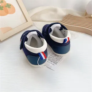 Vista trasera de zapatos de bebé azul marino con suela blanda y cinta tricolor.