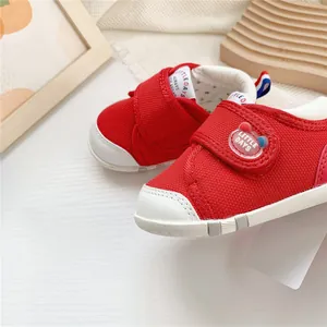 Primer plano de zapatos rojos para bebés con puntera blanca y tejido de malla suave.