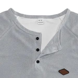 Close-up detail of men's grey waffle knit Henley shirt collar and textured fabric