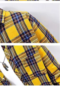 Macro detail view of yellow and blue plaid shirt fabric with feather necklace accessory