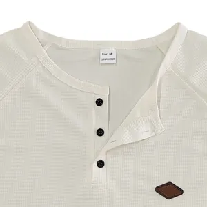 Dettaglio dello scollo di una maglia Henley bianca a nido d'ape con targhetta e bottoni