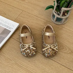 Sparkling gold glitter Mary Jane shoes for girls with elegant bow detail on wooden floor