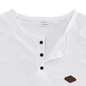 Dettaglio del colletto di una maglia Henley bianca in maglia a nido d'ape con bottoni
