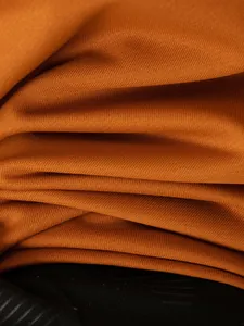 Gros plan sur les manches froncées d'un polo pour homme de couleur orange brûlé.