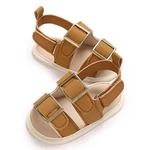 Dettaglio di sandali marroni per neonati in ecopelle con doppie fibbie metalliche e chiusura velcro