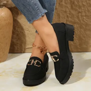 Detalle de primer plano de mocasines negros con plataforma y hebilla dorada en modelo