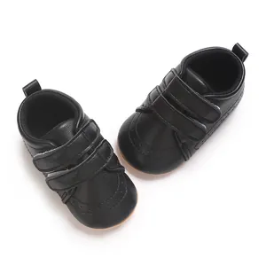 Dettaglio di scarpe da primi passi per neonati in pelle nera con doppia chiusura.