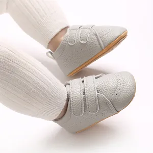 Dettaglio scarpe da camminata per neonati in pelle grigia con velcro e suola antiscivolo.