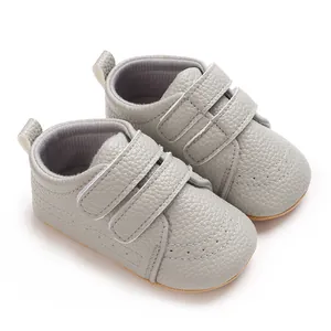 Dettaglio di scarpe primi passi grigie per neonati con cinturini in velcro e suola in gomma.