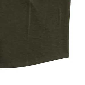 Close-up detail of dark olive green slub cotton fabric texture and hem on a men's polo shirt.