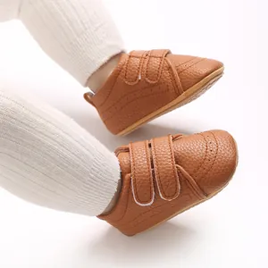Primo piano di scarpe primi passi in finta pelle marrone con chiusura a strappo