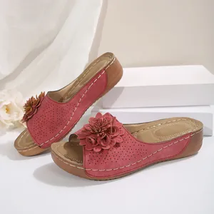 Détail des sandales à talons compensés rouges avec fleur et texture perforée.