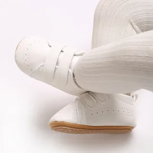Dettaglio di scarpine bianche in stile inglese per neonati con suola in gomma antiscivolo