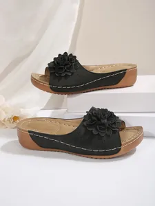 Vue latérale de sandales compensées noires avec fleur 3D et semelle aspect bois