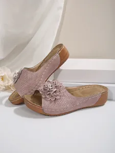 Détail de sandales compensées vieux rose avec perforations laser et une fleur décorative