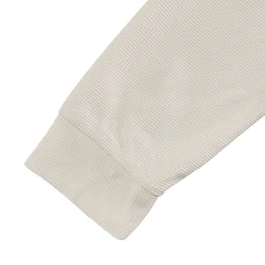 Dettaglio della trama a nido d'ape e del polsino a coste su una maglia avorio da uomo