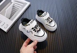 Gedetailleerd macro-overzicht van witte peutersneakers met schattig berenornament en leerfinish