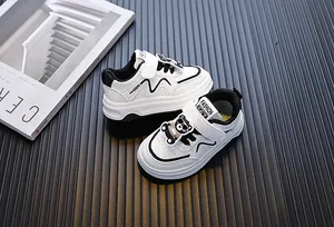 Detailopname van witte peutersneakers met decoratieve beer en handige klittenbandsluiting.