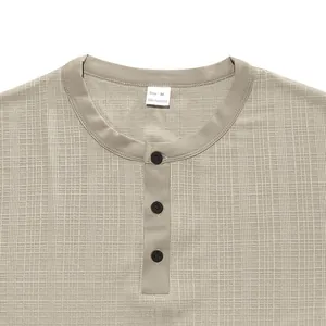 Vue détaillée en gros plan du tissu texturé et du col à boutons d'un t-shirt Henley pour hommes
