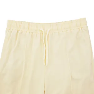 Detalle de la cintura elástica con cordón de unos pantalones de chándal crema para hombre