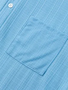 Detalle en primer plano de la textura azul claro y el bolsillo de una camisa de hombre