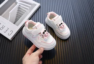Detailweergave van witte peutersneakers met roze accenten en schattige cartoon beer decoratie