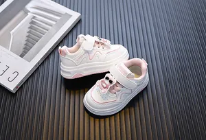 Detailweergave van witte en roze peutersneakers met schattig berenornamentje en klittenband